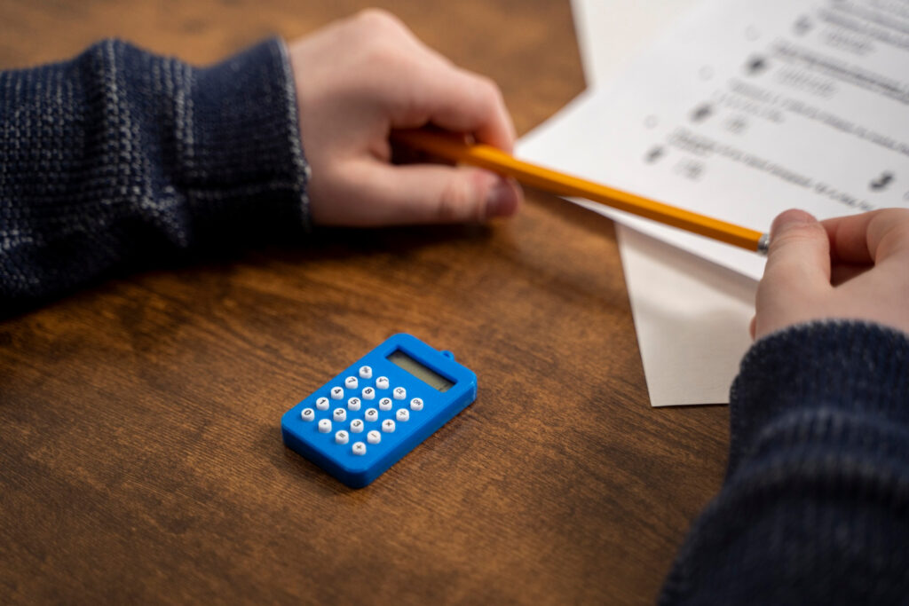 Student calculating total grade using a calculator and handwritten notes